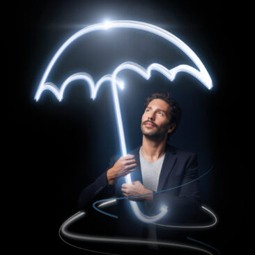 Le visu principal de la campagne Bâloise, un homme sur un fond noir qui tient un parapluie qui se forme par la lumière.